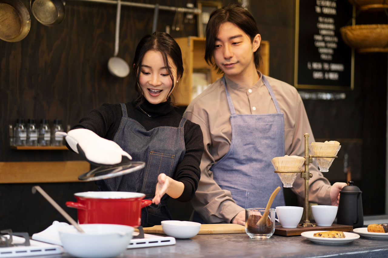 Hombre y mujer japoneses con utensilios de cocina cocinando en un restaurante